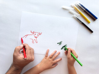 Father and child create animal drawing together using vibrant markers