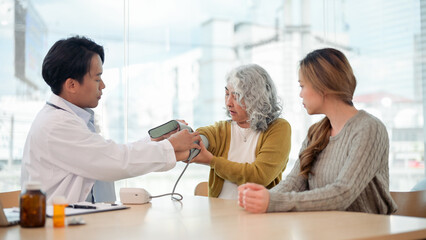 Fototapeta premium A retired grandmother having her blood pressure measured by a monitor while visiting the doctor.