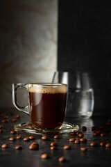Espresso, glass of cold water, and roasted coffee beans.