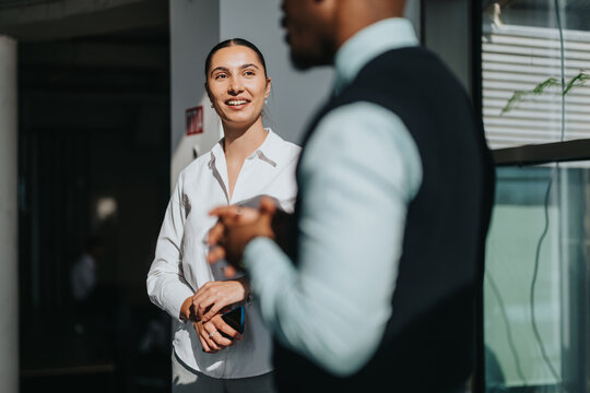 Multiracial business workers engage in a friendly discussion in a modern office setting. The image captures teamwork, communication, and professional collaboration in a bright and positive environment