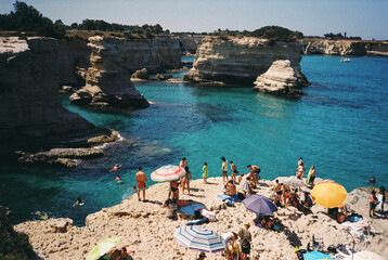 Tourists relaxing on torre sant'andrea beach, puglia, italy, on film photography