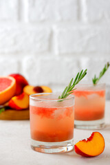 Homemade grapefruit, peach drink lemonade with rosemary in a glasses on a light table. Healthy drink, sugar and alcohol free. Vertical orientation.