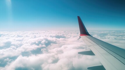 Obraz premium Airplane wing above fluffy clouds and blue sky.