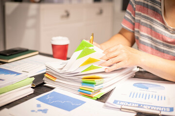A man works overtime at his desk in the office of the office to clear documents to send to the customer. During work, he is stressed from work and happy after finishing the work for the customer.