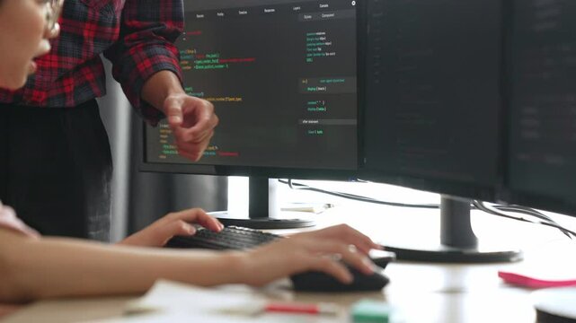 Back end or software developer manager supervising his team on new application program development on debugging and solving complex code algorithms on monitor. Burgeoning