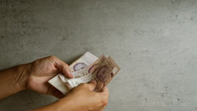Hands holding singaporean dollars against a concrete background, emphasizing currency and financial context