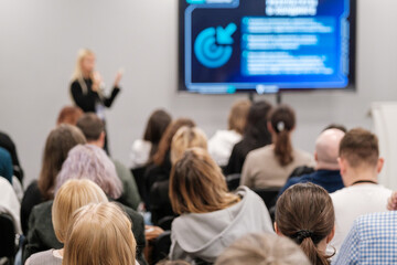 Blurred image of people listening to a business presentation in a conference setting. The speaker...