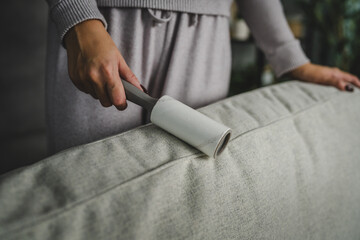 close up of woman clean sofa with lint roller