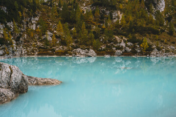 A rocky shoreline with a body of water that is blue in color lake sorapis dolomites