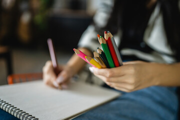 Woman sketch and draw on a blank notebook with a wooden crayon in hand