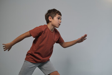 A young boy in an energetic stance, appearing ready to leap or run, captured in a minimalist indoor...