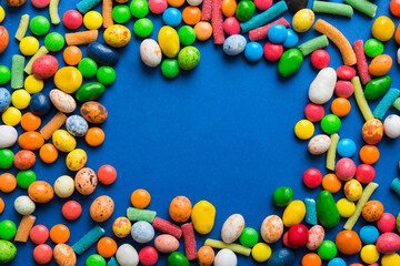 Obraz premium Mixed collection of colorful candy, on colored background. Flat lay, top view. frame of colorful chocolate coated candy