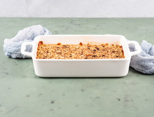 Oatmeal porridge granola cake in white baking tray on green
