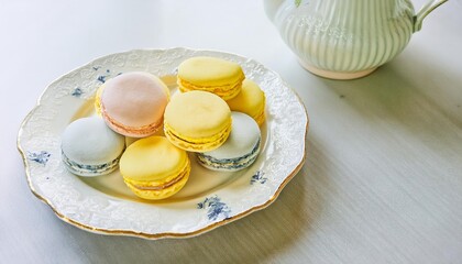 Colorful french macarons resting on elegant plate with teapot nearby