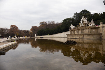 A pool with different statues, and in the background people are walking