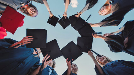 Obraz premium College graduates put their caps together and then toss them up.