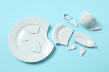 White cup and plate broken on color background