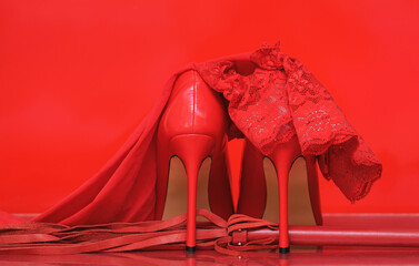 red high heels and whip on red background