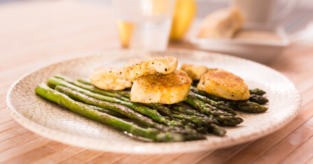 Fried chicken breast pieces with asparagus on white plate