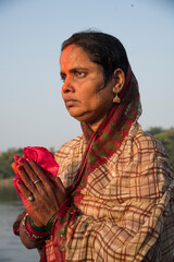 Traditionally dressed Indian woman pray into the river on Chhat Puja Festival.