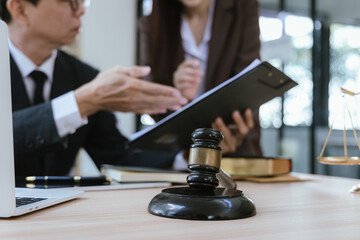 Male lawyer giving legal advice, working with businesswoman in office, contract documents and wooden hammer on table in courtroom. Justice and law. Judge in suit or lawyer working with documents. Law.