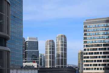 Naklejka premium Modern high-rise buildings with unique rounded architecture under a clear blue sky.