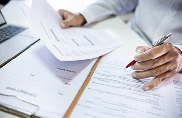 Close up shot, asian businessman reviewing document reports at office with computer laptop. legal expert, professional lawyer reading and checking financial documents or insurance contract
