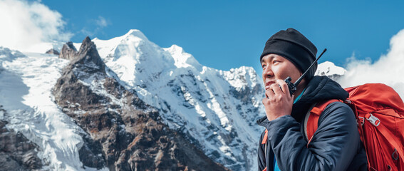 Portrait of Sherpa man with backpack using walkie-talkie for calling rescue helicopter with Mera...
