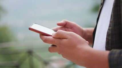 4K Closeup shot of hands of an Indian man scrolling on his mobile phone while standing outdoors. Man does scrolling gesture on touch screen of smart phone to move through the page or app. 
