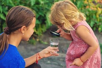 A child looks at water through a magnifying glass. Selective focus.