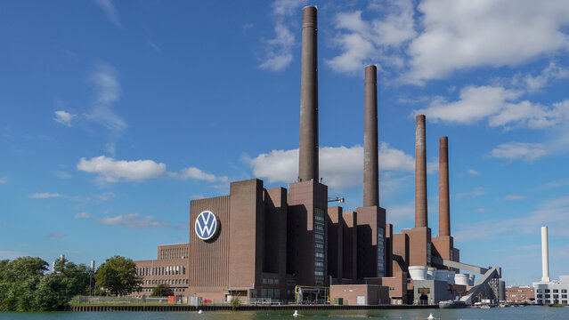 Wolfsburg, Germany - September 30.2024: View of the production plant of the Volkswagen headquarters in Wolfsburg with dock and canal in the foreground and large Volkswagen logo on the factory facade