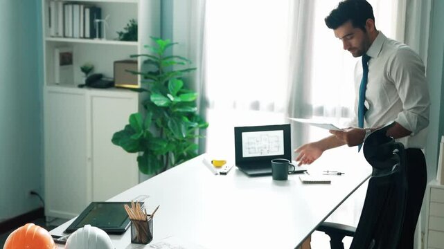 Architect engineer using laptop planning house design at office while sitting at meeting table with blueprint and equipment scatter around.Skilled civil engineer working at blueprint. Alimentation.