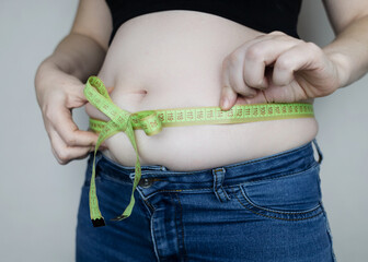 Obesity and overweight from overeating. Big belly tied with measuring tape as a gift. Body fat from candies and sweets
