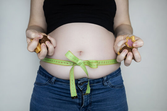 Obesity and overweight from overeating. Big belly tied with measuring tape as a gift. Body fat from candies and sweets