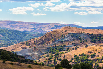 Fototapeta premium Scenic view of Hattusa's surroundings with rolling hills, sparse vegetation, winding paths, and a clear sky with scattered clouds. Bogazkale, Corum, Turkey (Turkiye)