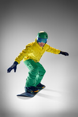 Snowboarder, young athletic man, in yellow jacket and green pants executing trick in mid-air...