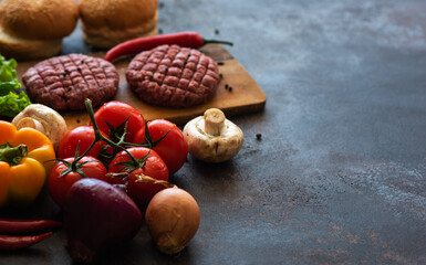 Fast food. Ingredients for making homemade fresh juicy burger. Top view and flat lay on a black table. Raw minced meat, spices, bun, lettuce and fresh vegetables.