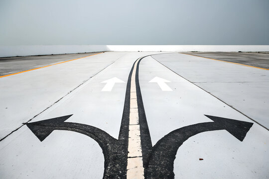 Diverging roads illustrate choices ahead on a plain surface under soft sunlight