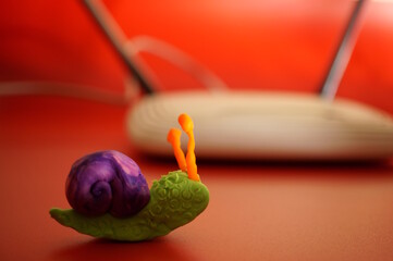 A toy snail made of plasticine on the background of a WiFi router.