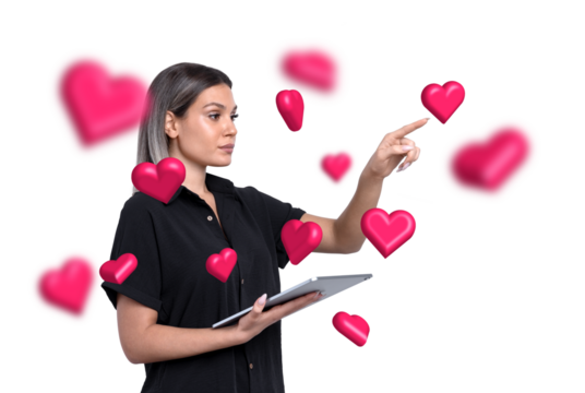 Woman pointing at floating pink hearts while holding a tablet, isolated on a white background. Concept of love, interaction, and technology - Powered by Adobe