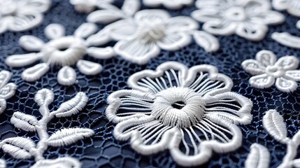 Close-up of intricate white lace floral embroidery on dark navy blue fabric.