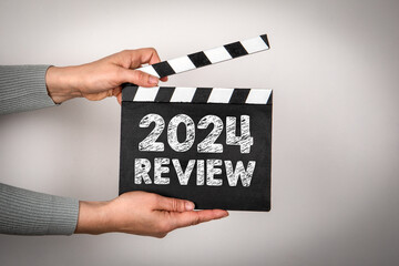 2024 Review Concept. Female hands holding movie clapper