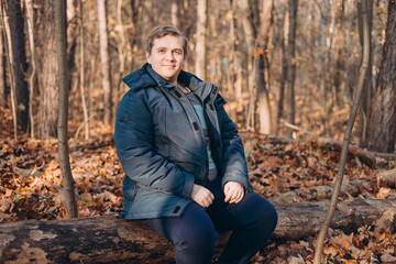 30s Plus size male smiling outside on an adventure. Hiking, lifestyle, adventure and tourism concept. Young man standing in woodland and looking at the camera, autumn time