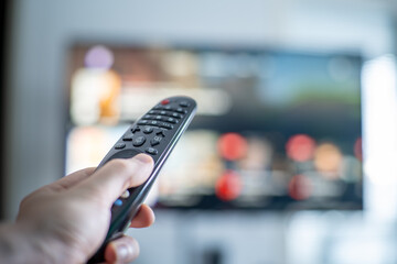 Person changing tv programs by using smart tv remote control. Close up view.