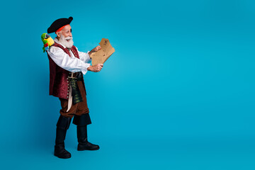 Full body photo of bearded pirate man hold treasure map wear hallooween costume isolated on blue...