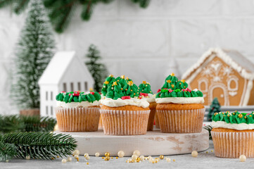 Christmas tree and wreath shaped cupcakes with candy sprinkles on top. Christmas dessert on a light concrete background.