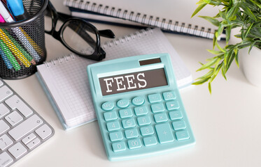 A calculator with the inscription FEES is placed in the stack of documents. Business concept