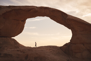Man walking on rocks in the desert of the wadi rum in jordan at sunset