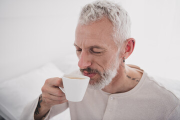 Mature man enjoying a peaceful morning coffee at home in his pajamas, feeling relaxed and refreshed