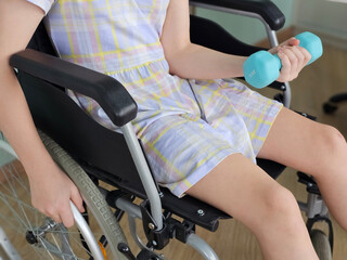 Child in wheelchair doing exercises with dumbbells concept